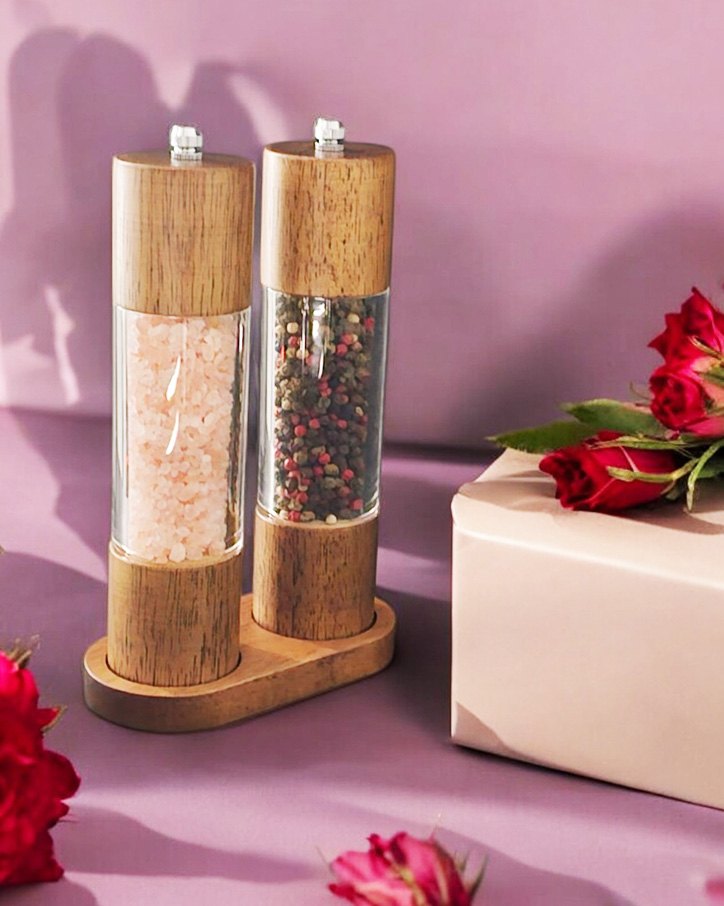 Grinder pair on a pink surface beside a wrapped gift and red roses