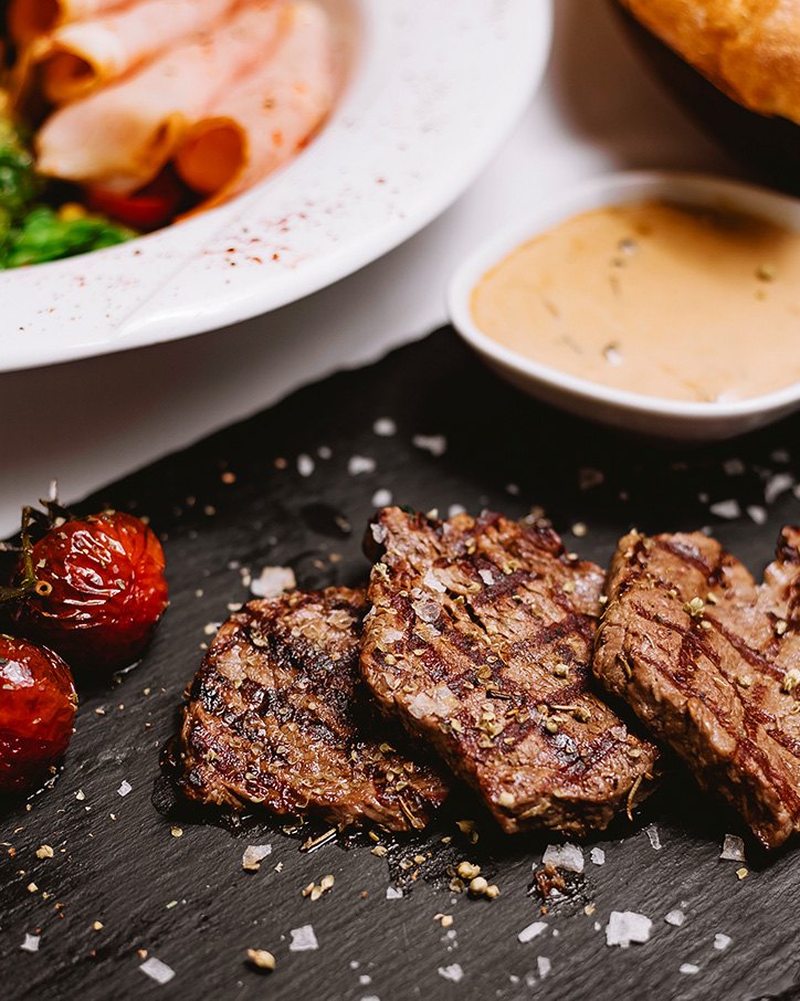 Grilled steak slices seasoned with salt and pepper on slate
