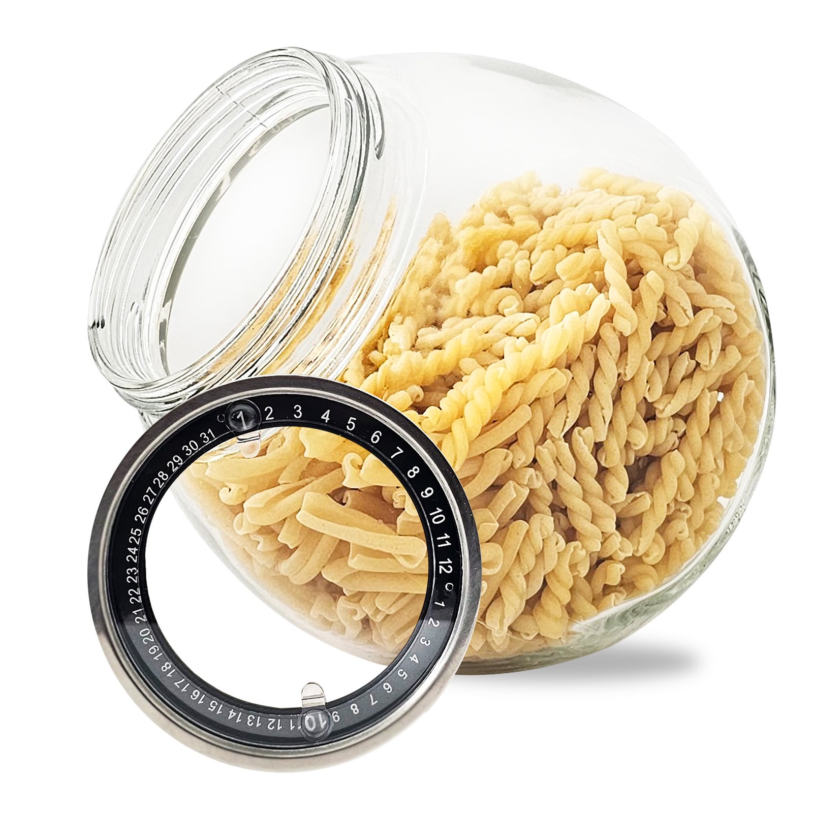 Glass tilted jar filled with fusilli pasta with a stainless steel dial lid propped in front on white