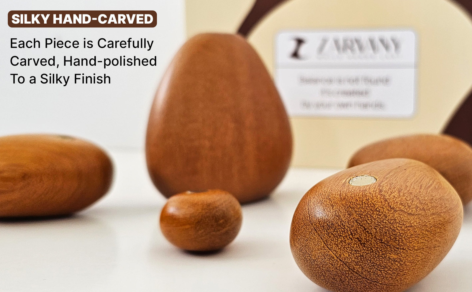 Close-up of polished wooden stones on a white surface with the brand box behind