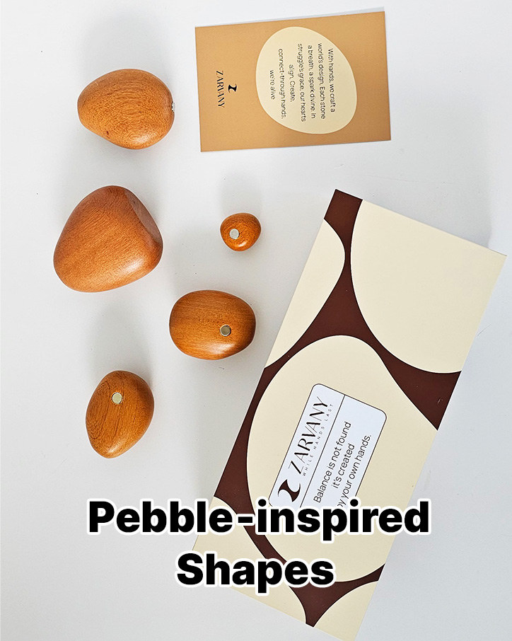 Wooden pebble shapes beside the box on a pale surface, labeled Pebble-inspired Shapes