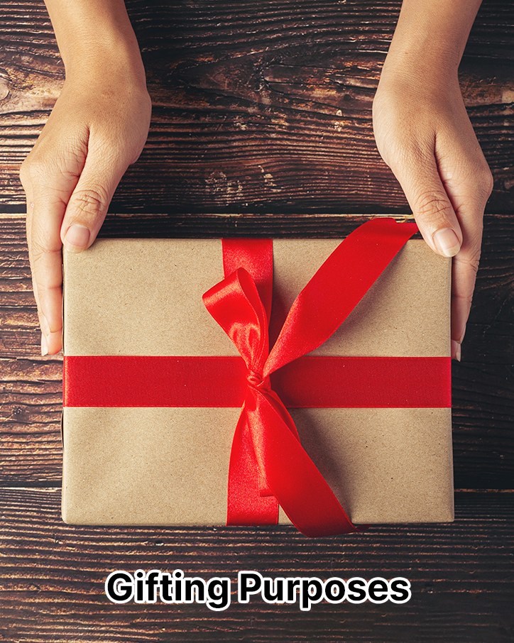 Hands holding a wrapped gift box with a red ribbon on a dark wooden table, labeled Gifting Purposes